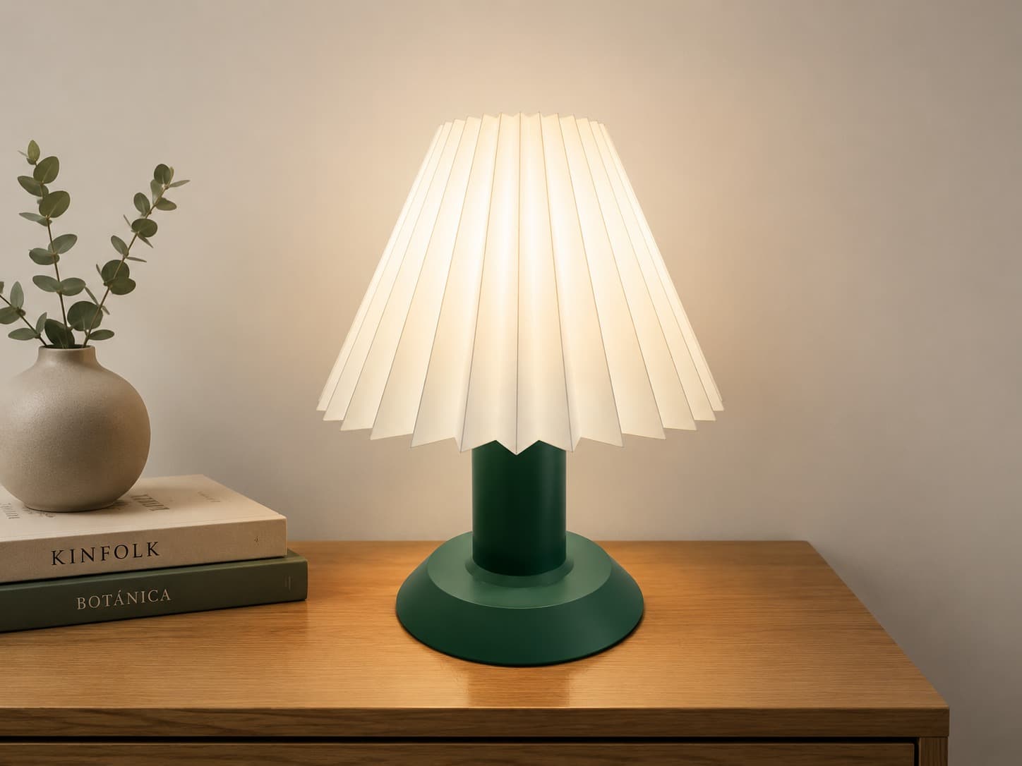 Lámpara Arquera de pantalla plisada y base verde sobre una cómoda